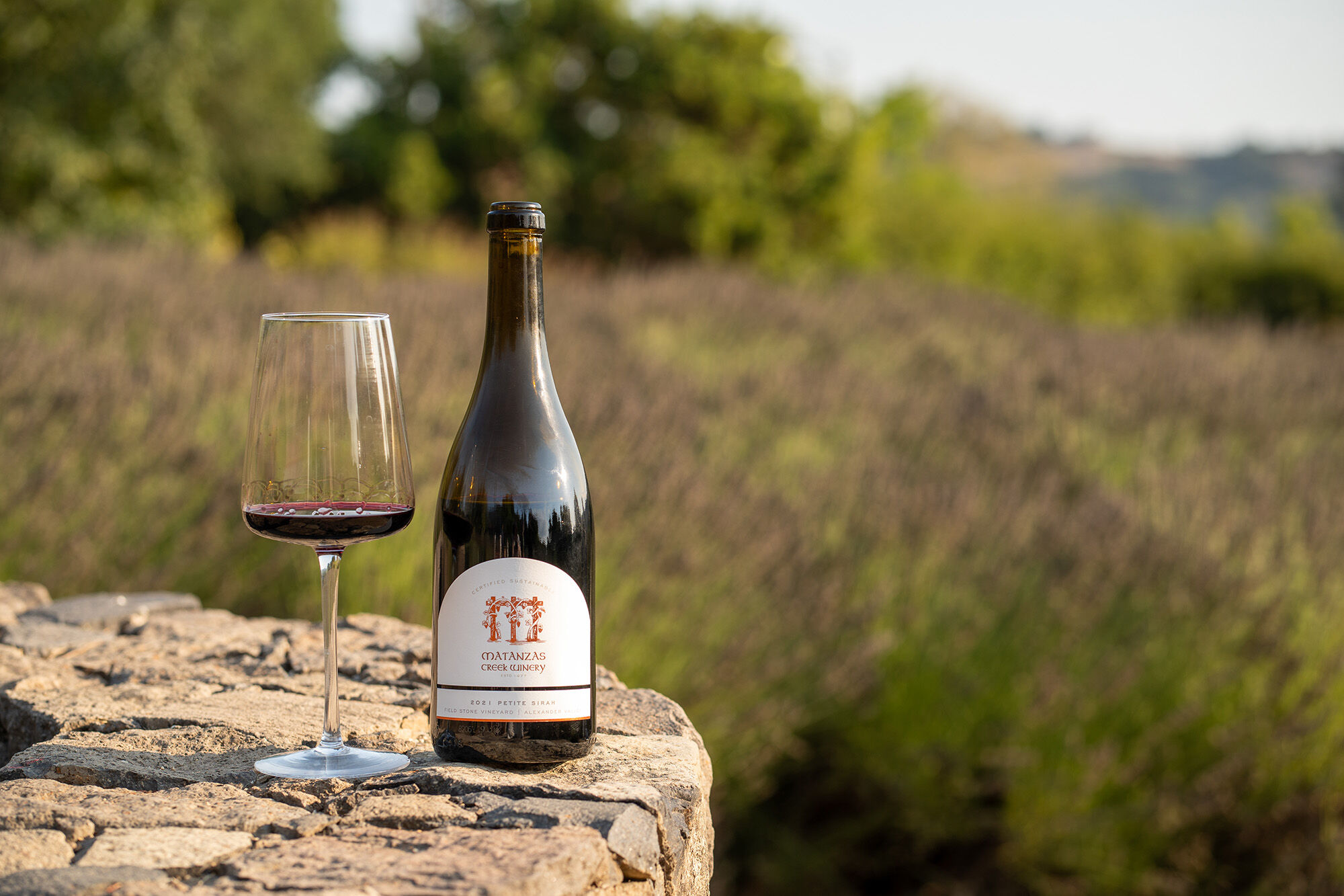 An elevated wood patio with three adirondack chairs on the ground.